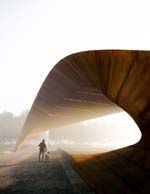 Arching over Luther George Park's Central Plaza, the Performance Pavilion fosters a journey between downtown Springdale, Arkansas, and the active edge of Spring Creek.