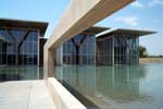 Architectural concrete beams and columns frame the view toward the galleries and reflecting pond, as seen from the café terrace.